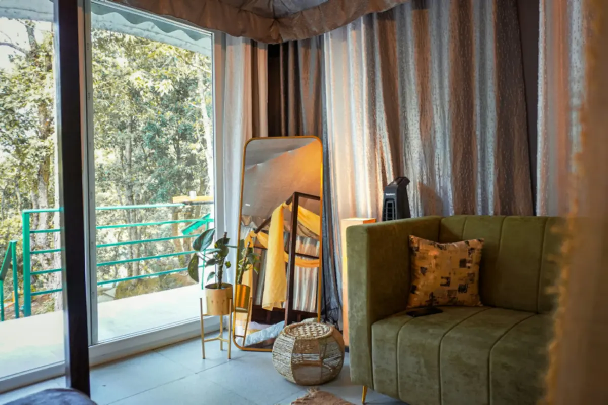 Junior suite ở Huế: góc tiếp khách với sofa nhung xanh rêu, gối tựa và cửa kính lớn nhìn ra hàng cây