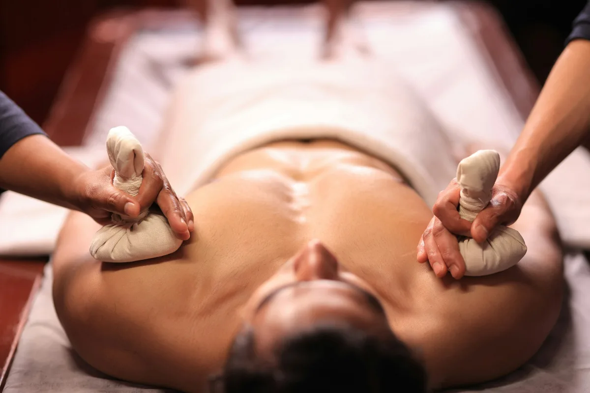 Kỹ thuật viên chườm túi thảo mộc ấm lên vai khách tại Spa Ngự Uyển, spa ở Huế